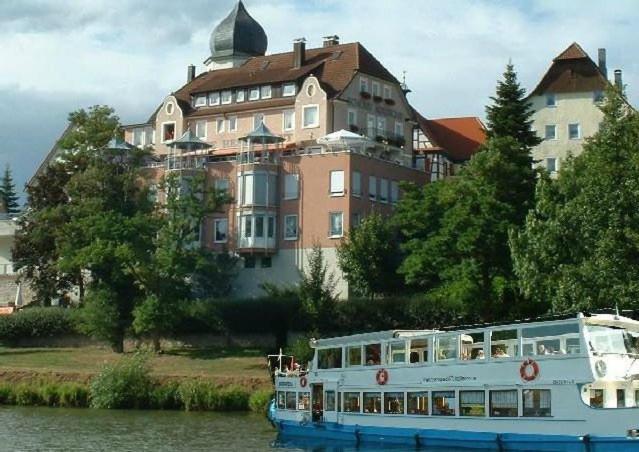 un barco en el agua frente a un gran edificio en Apartments mit Klimaanlage am Neckarufer, Schöne Aussicht en Bad Friedrichshall