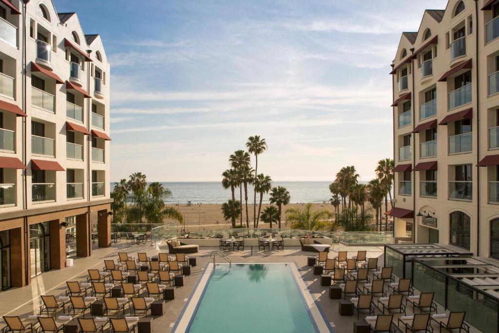 a patio area with chairs, tables, and a pool at Loews Santa Monica Beach Hotel in Los Angeles