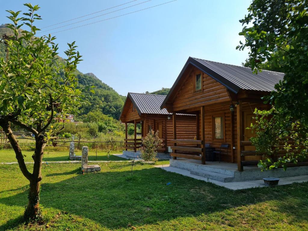 a wooden cabin in a field with a tree at Little Paradise in Virpazar