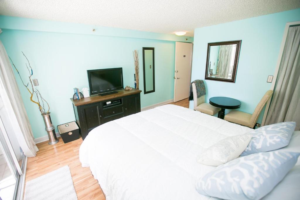 sypialnia z białym łóżkiem i telewizorem w obiekcie Kuhio Village 806 w mieście Honolulu
