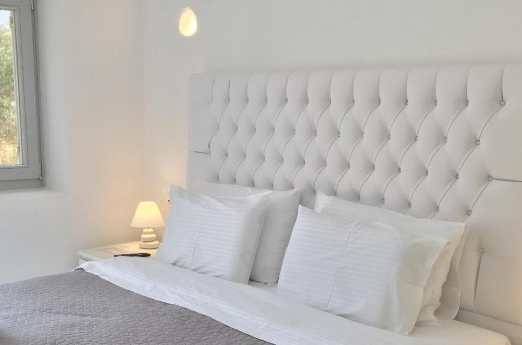 a white bed with white pillows in a bedroom at Ariana Eco Suites Adults Only in Fira