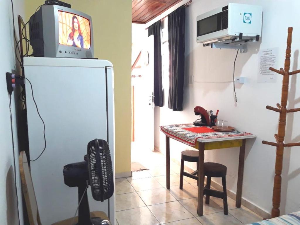 Habitación con mesa pequeña y nevera con TV. en Infinito Suíte en São Paulo