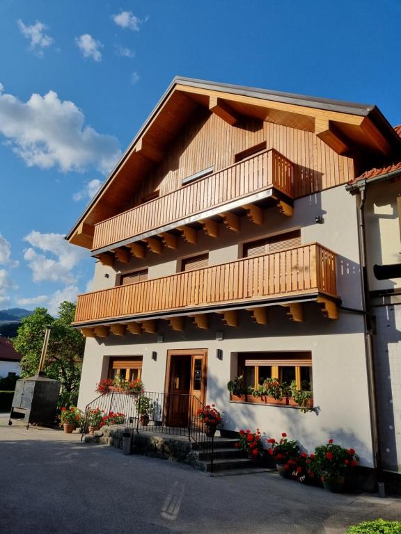 um edifício com uma varanda e flores sobre ele em Rooms Pevc & Hostel Ljubno ob Savinji em Ljubno