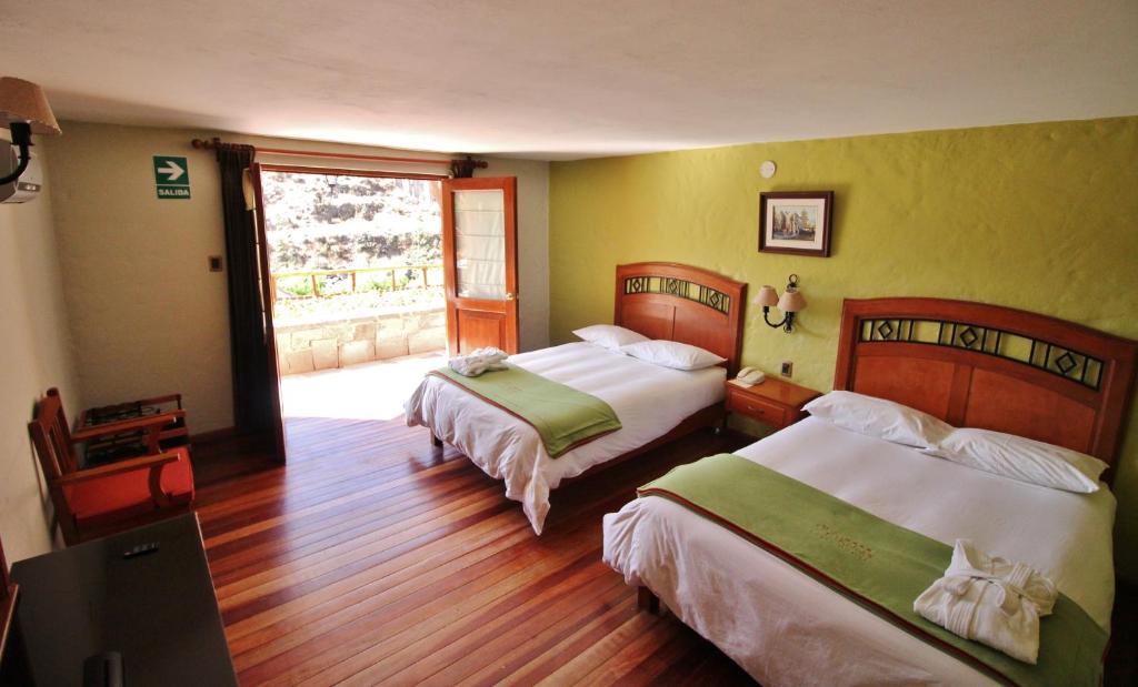a hotel room with two beds and a balcony at Hotel El Refugio in Chivay