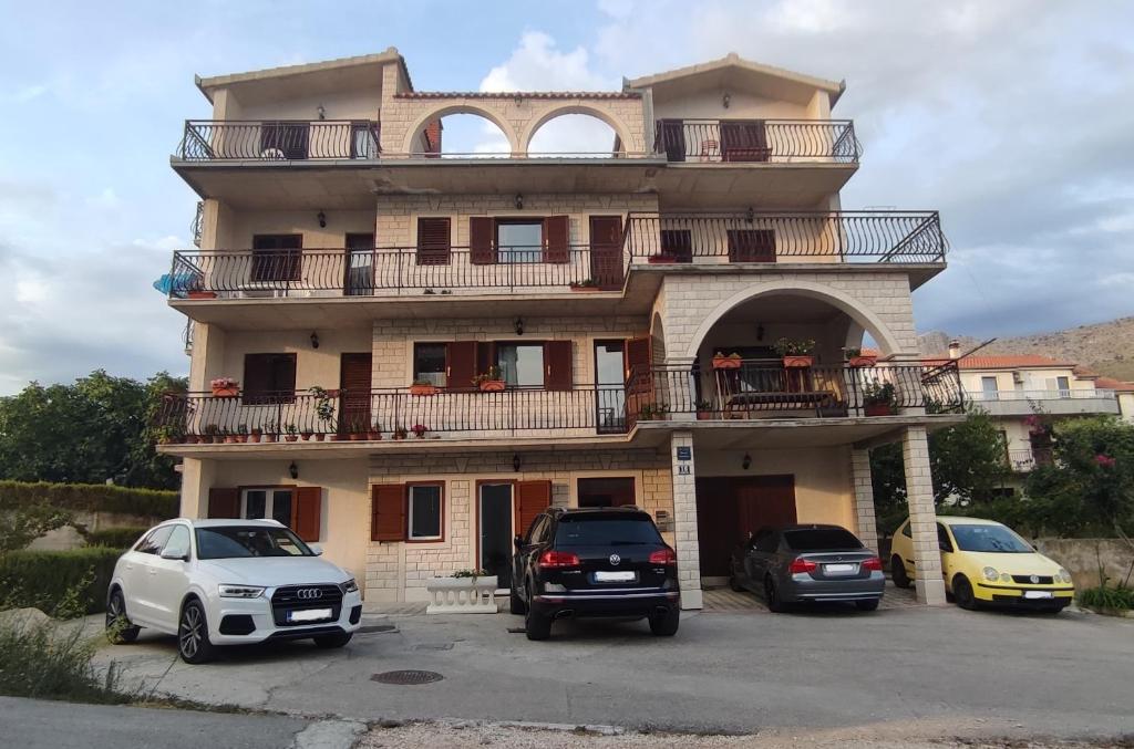 a building with three cars parked in a parking lot at Apartments Villa Anna in Podstrana