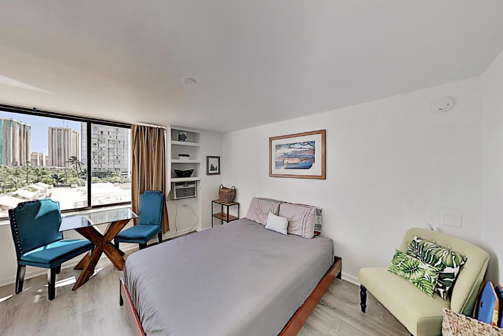 een slaapkamer met een bed, een bureau en stoelen bij Hawaiian Monarch 805 condo in Honolulu