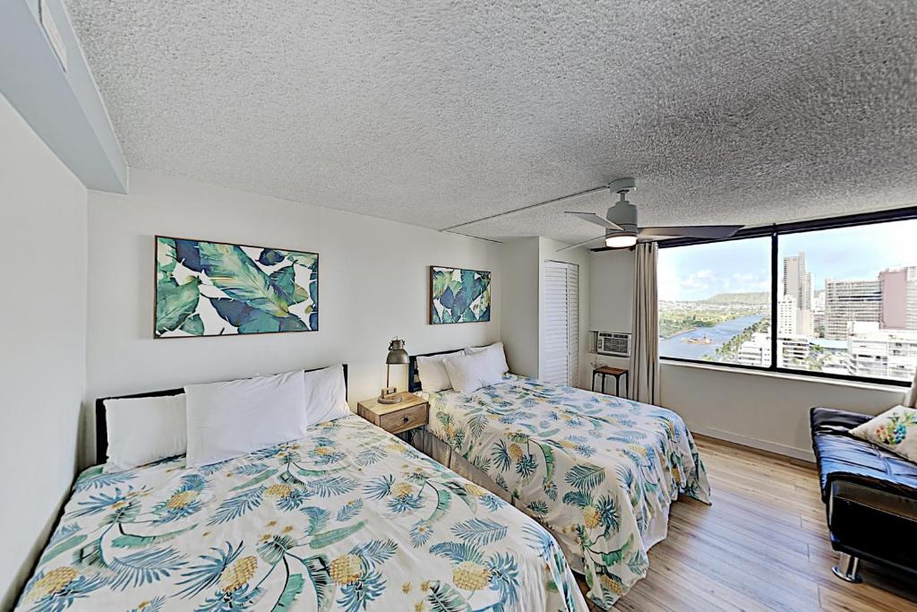 a bedroom with two beds and a large window at Hawaiian Monarch 2108 condo in Honolulu