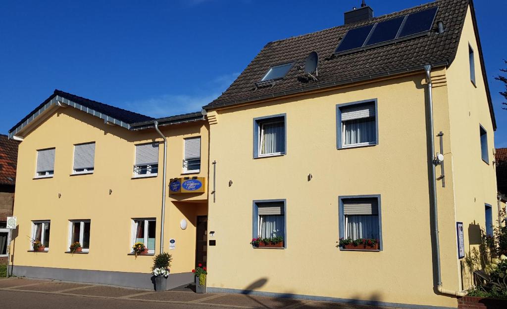 un edificio amarillo con ventanas y flores en los escaparates en Landhaus Effeld en Wassenberg