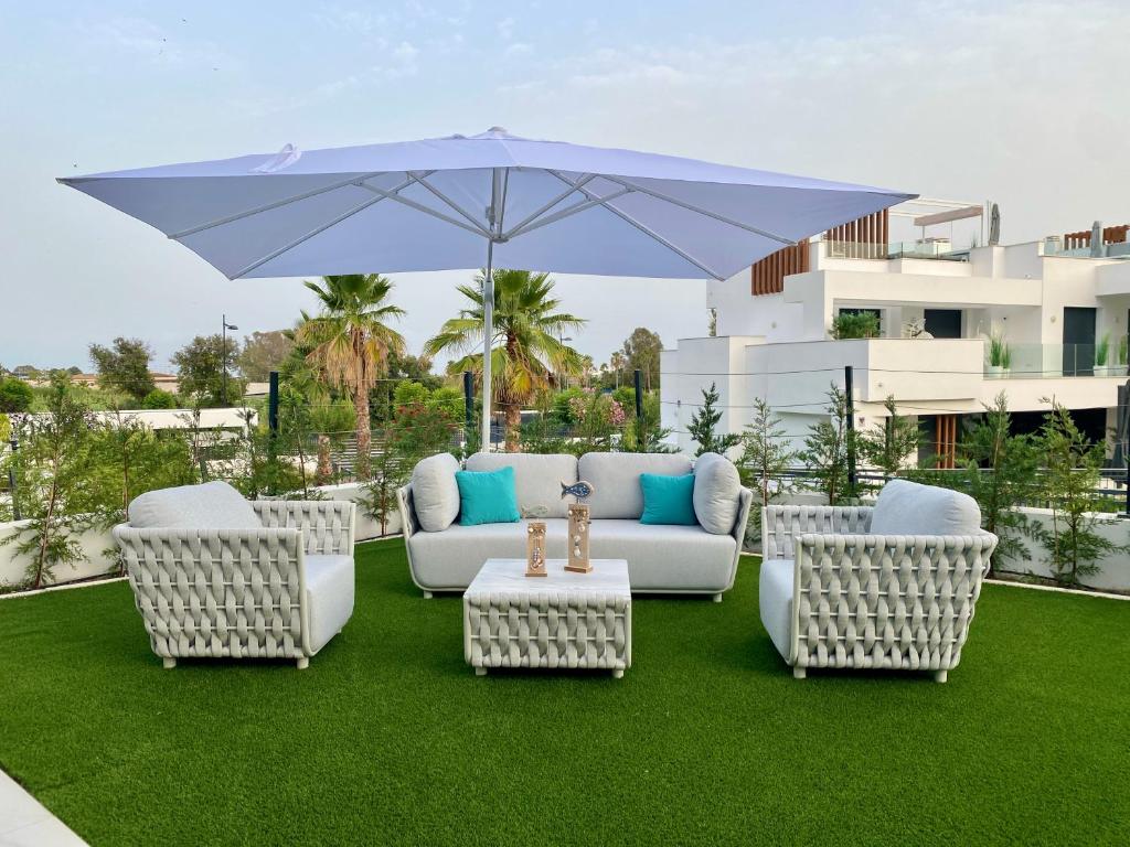 a patio with a couch and chairs and an umbrella at Miradores del Sol in Estepona
