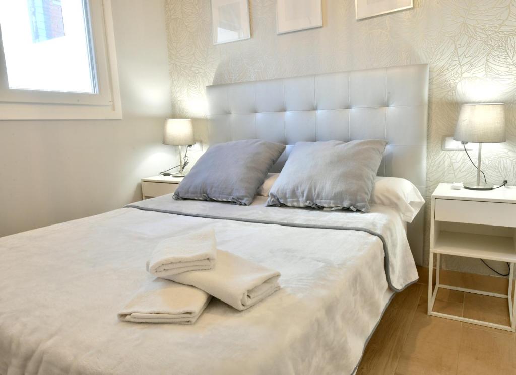 1 dormitorio con 1 cama blanca y 2 toallas en MS4 Apartamentos Nervión, en Sevilla