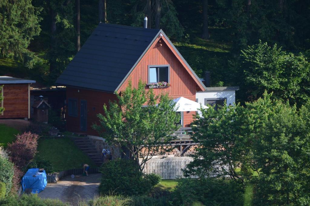 une maison rouge avec un toit noir dans l'établissement Chata u rybníka, à Trutnov