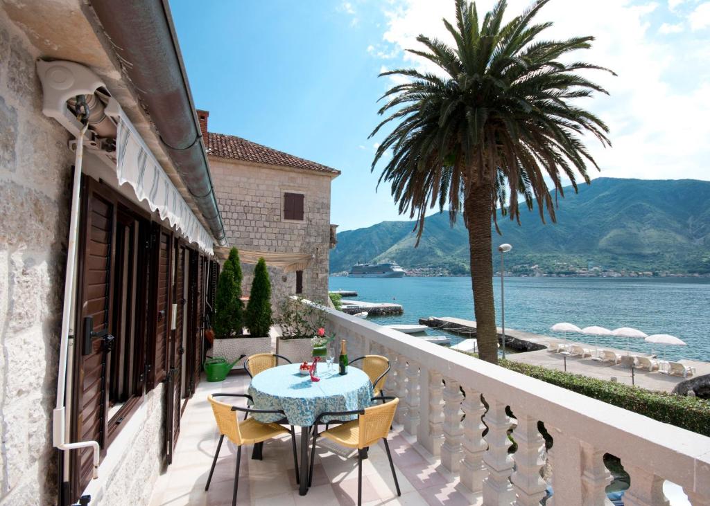 einen Balkon mit einem Tisch, Stühlen und einer Palme in der Unterkunft Apartments Radonicic in Kotor