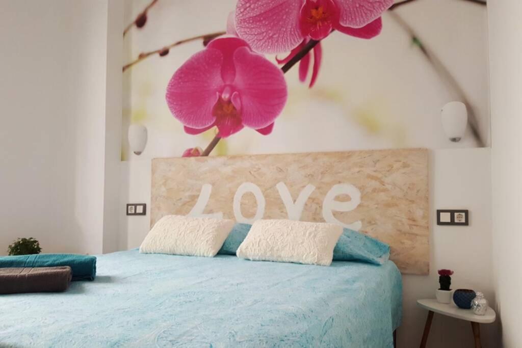 una camera da letto con un letto con fiori rosa sul muro di SUITE JINETES a Málaga