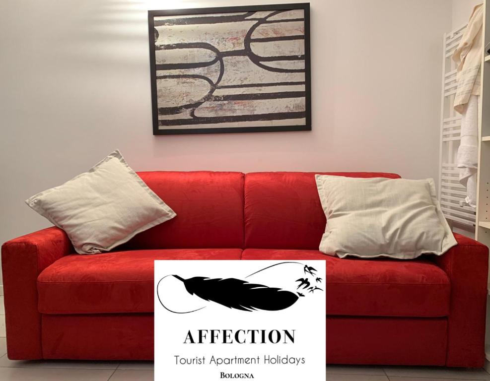 um sofá vermelho com um cartaz à frente. em Affection Apartment em Bolonha