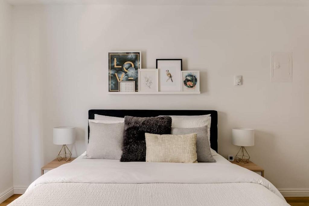 a white bedroom with a bed with pictures on the wall at Sophisticated Long Beach Suite with Patio Dining and Parking NRP21-00185 in Long Beach