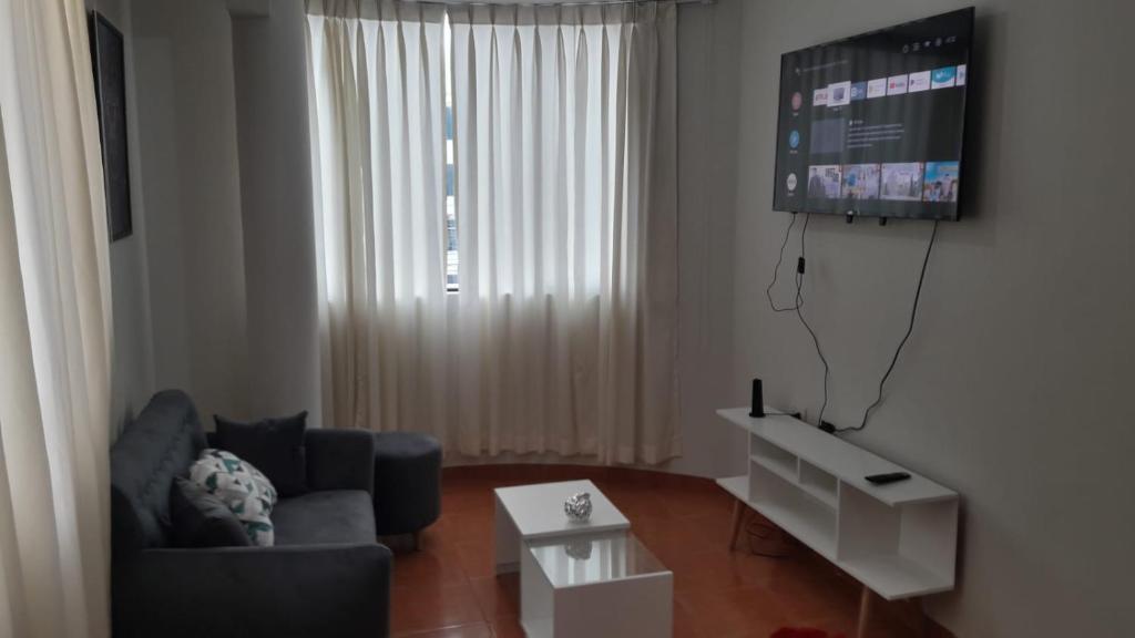 Una sala de estar con un sofá y un televisor de pantalla plana. en Hermoso departamento en chorrillos, en Lima