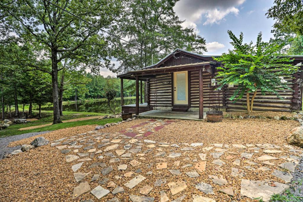 a log cabin with a stone path in front of it at 1950s Serenity Pond Cabin with View Peace and Quiet! in Talladega