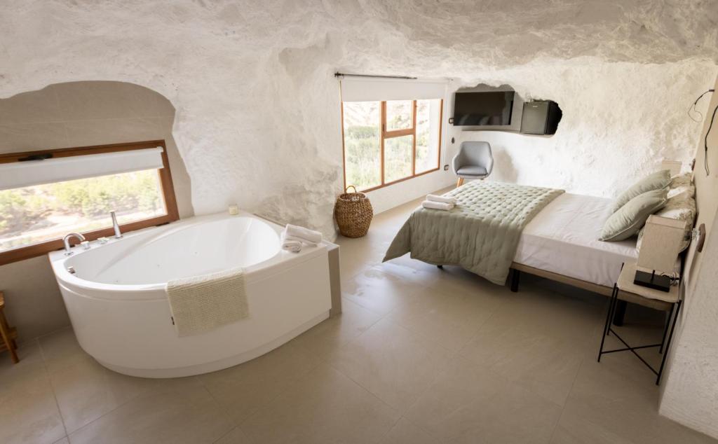 uma casa de banho com uma grande banheira ao lado de uma cama em Casa túnel Nido de Águilas em Alcalá del Júcar