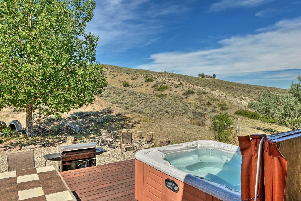 a hot tub on a deck with a hill at Exquisite Log Home with Lander Valley Views! in Lander