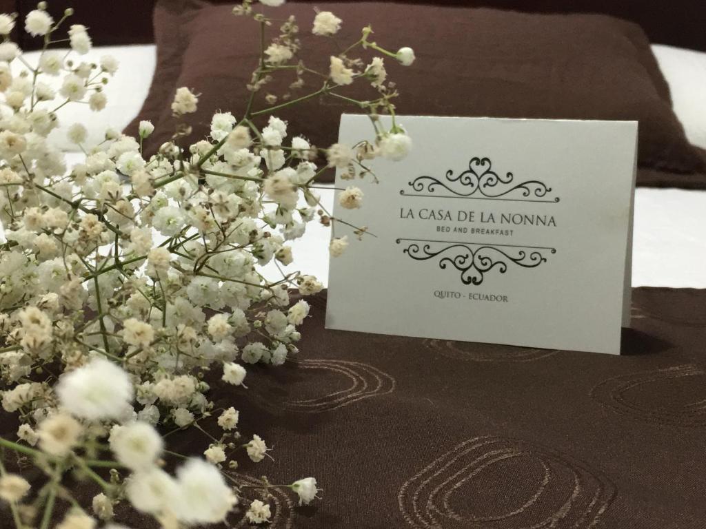 a sign next to a bouquet of flowers on a bed at La Casa De La Nonna in Quito