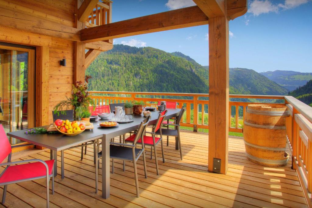 een houten terras met een tafel en stoelen erop bij Chalet Sabaroc - OVO Network in La Giettaz