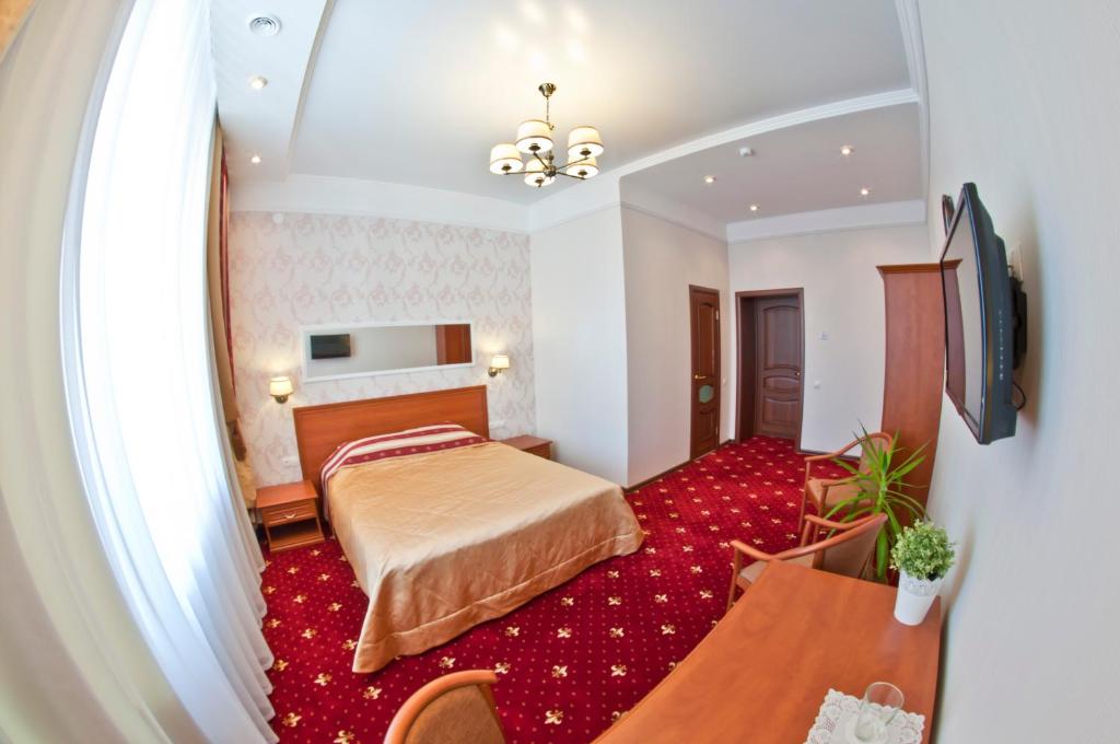 1 dormitorio con 1 cama y alfombra roja en Milyutinsky Hotel, en Cherepovets