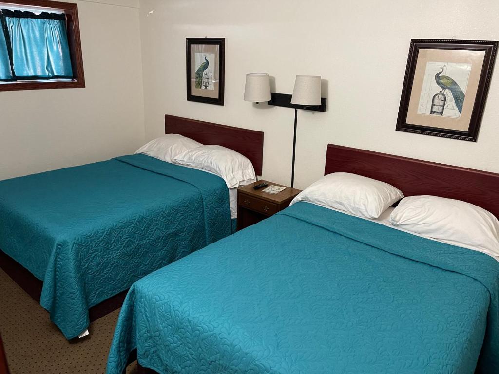 2 camas en una habitación de hotel con sábanas azules en Highland Court Motel en Fairmont