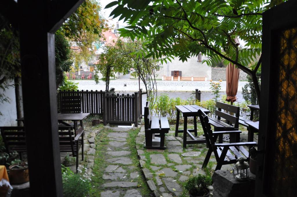 a patio with benches and tables and a river at Guest House Olšakovský in Český Krumlov