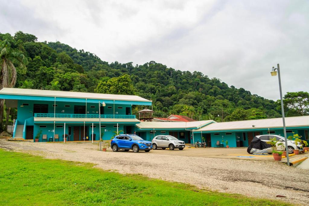 un edificio azul con dos coches estacionados frente a él en Hotel Don Fito, en Golfito