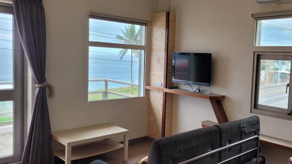 a living room with a couch and a tv and windows at Runners&#39; House Taitung in Changbin