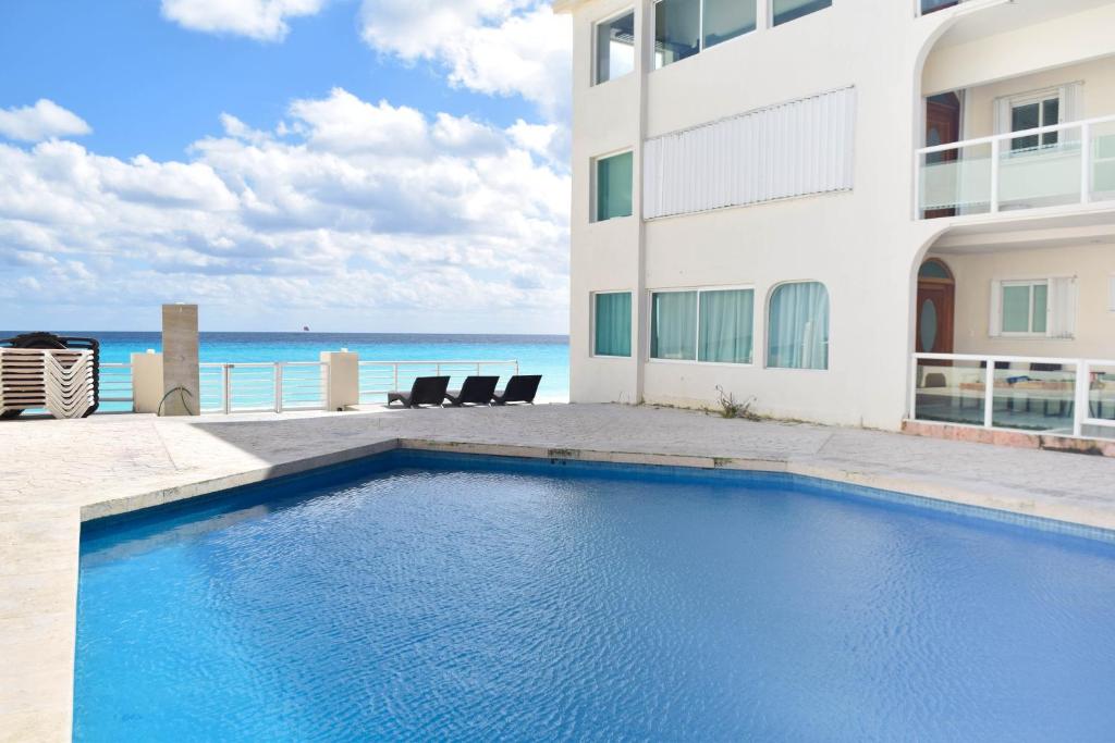 a swimming pool in front of a building with the ocean at Departamento sobre la playa Cancun in Cancún