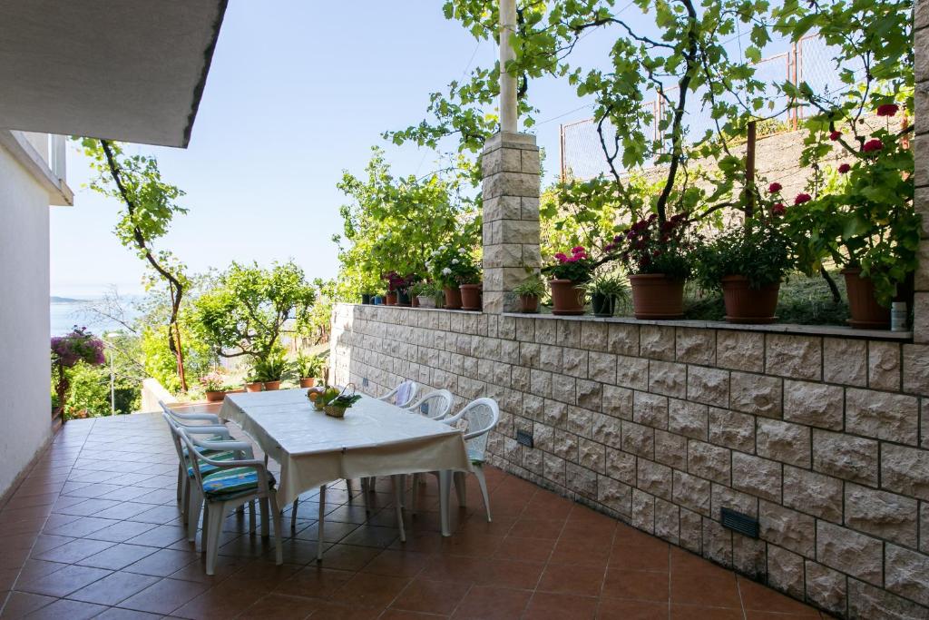 a patio with a table and chairs on a brick wall at Apartmani Kate, Plat in Mlini