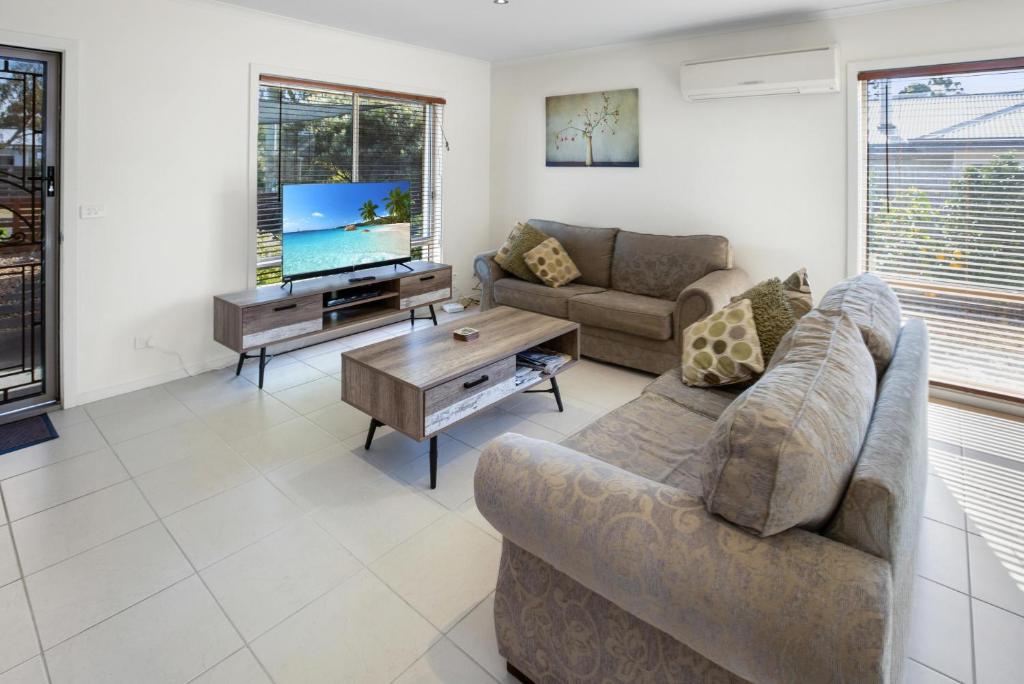 a living room with two couches and a tv at Paynesville Villa in Paynesville
