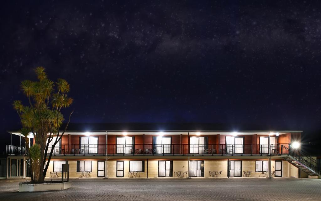 um edifício com uma árvore em frente à noite em Heritage Court Motor Lodge Oamaru em Oamaru