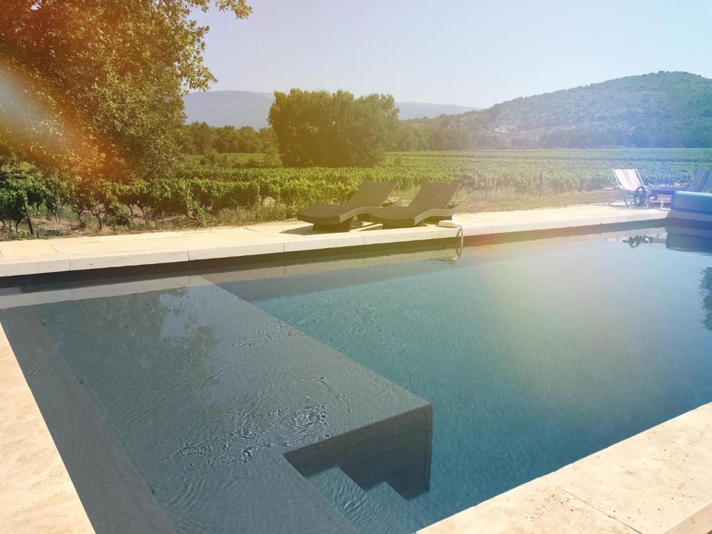 - une piscine avec des chaises et une vue sur un vignoble dans l'établissement Entre Vignes et Collines, à Méthamis