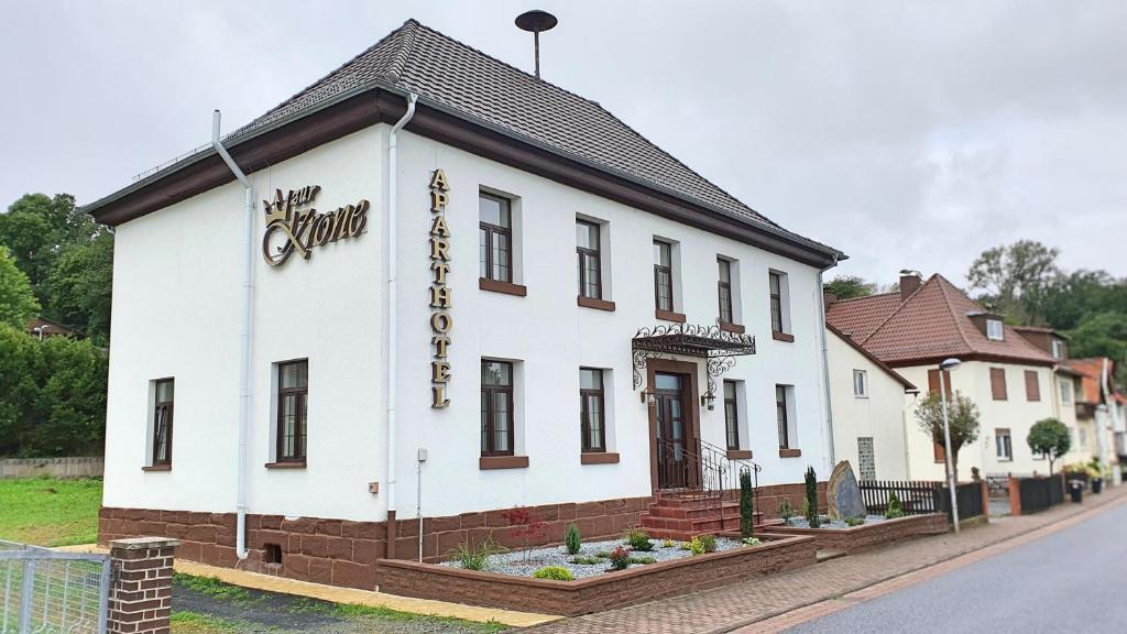 ein weißes Gebäude an der Straßenseite in der Unterkunft Zur Krone Aparthotel in Widdershausen