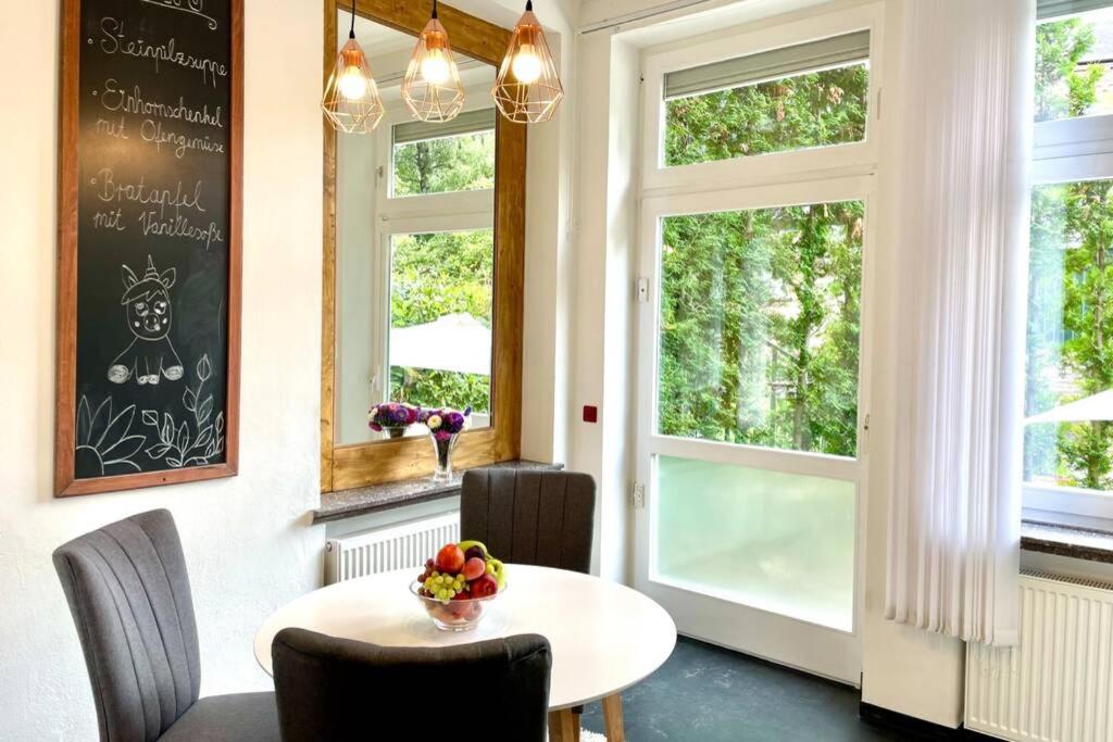 uma sala de jantar com mesa, cadeiras e janelas em Villa Einhorn: Altstadt Loft mit privater Terrasse em Goslar