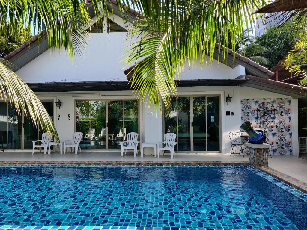 a swimming pool with chairs and a house at The Snug & The Sierra Airportel in Nai Yang Beach