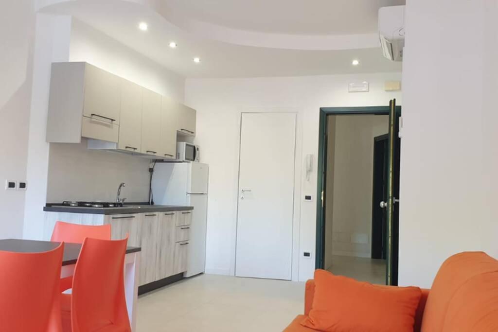 uma cozinha e uma sala de estar com cadeiras laranja em APPARTAMENTO NUOVO CENTRALISSIMO 150 MT DAL MARE em Lido di Jesolo