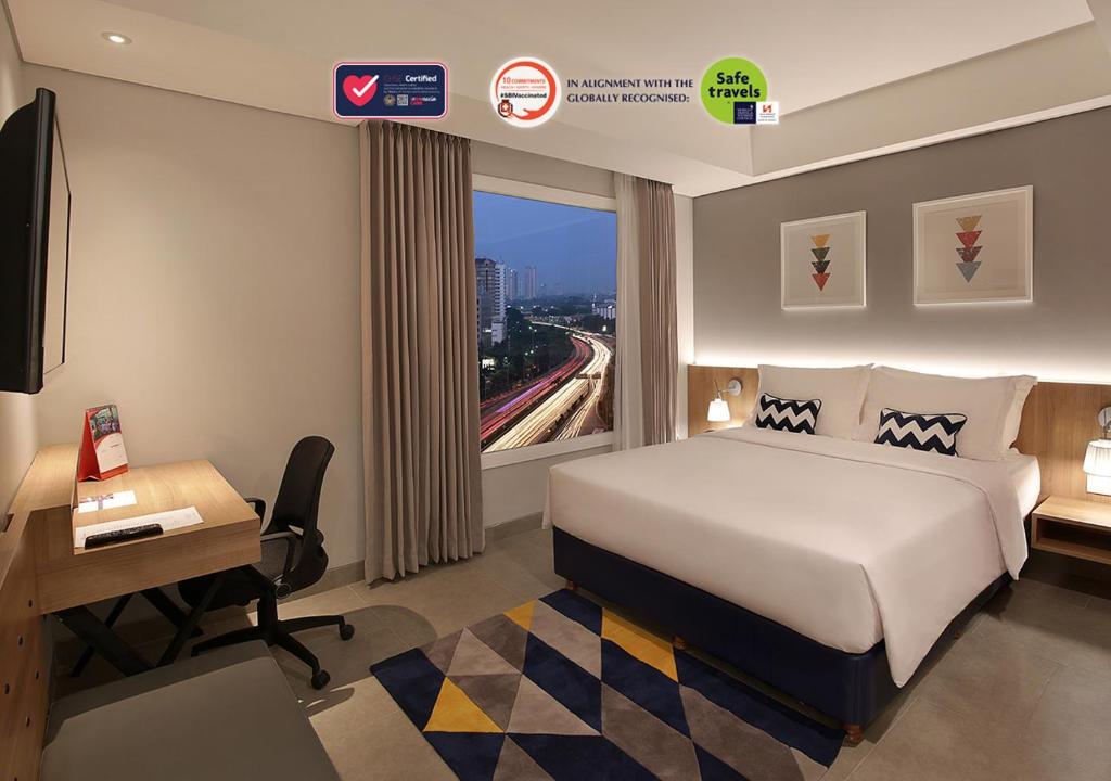 a hotel room with a bed and a desk and a window at Swiss-Belinn Simatupang in Jakarta