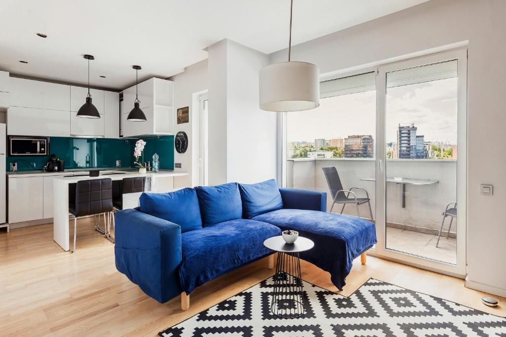 a living room with a blue couch and a kitchen at DD Apartments in Cluj-Napoca