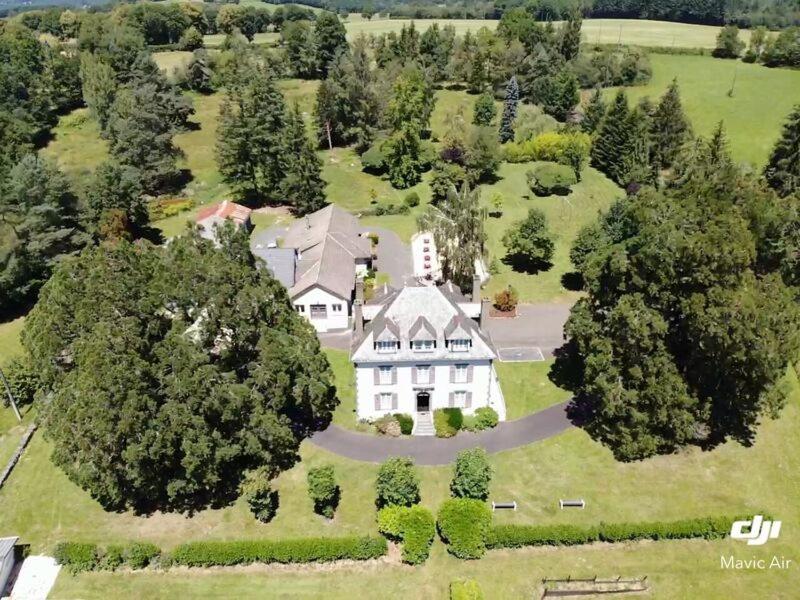 eine Luftansicht eines großen weißen Hauses mit Bäumen in der Unterkunft HOSTELLERIE LA BRUYERE in Chalvignac