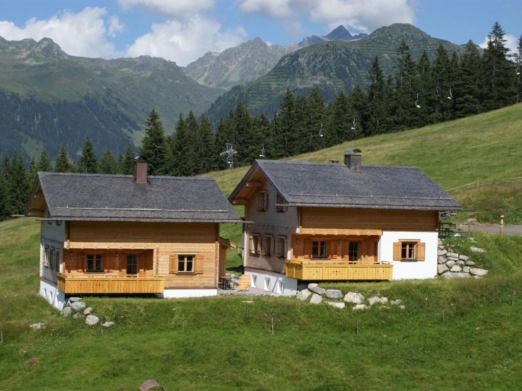 a house in a field with mountains in the background at Apartment with balcony in Sankt Gallenkirch in Sankt Gallenkirch