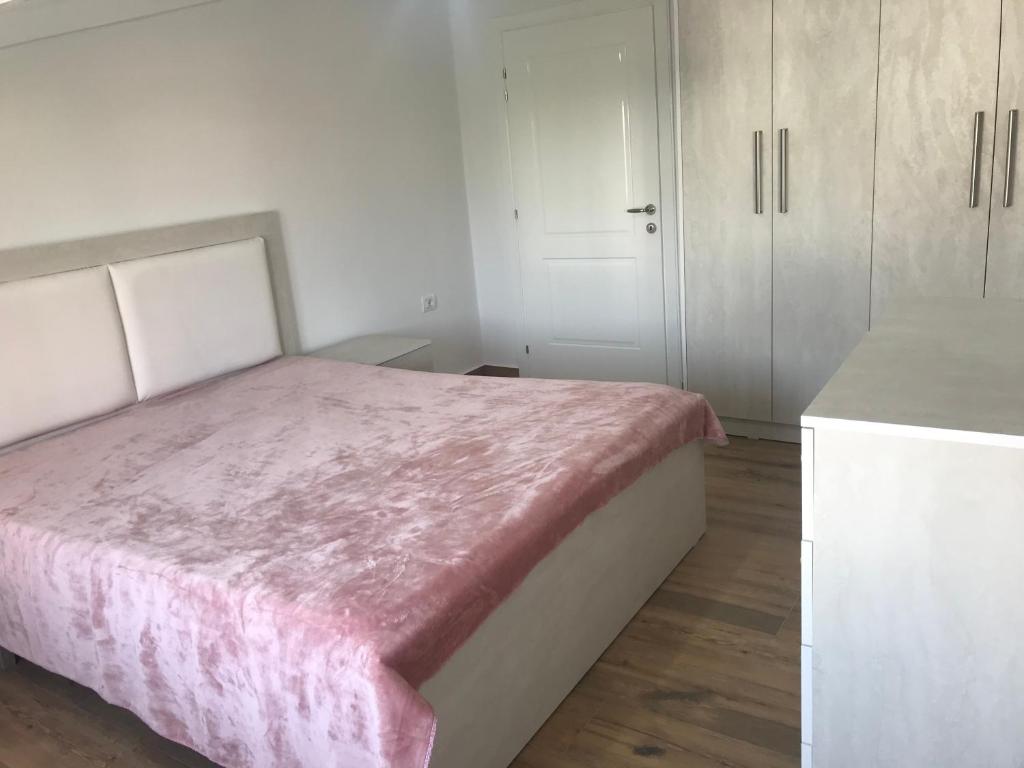 a bedroom with a pink bed and white cabinets at Flat Elbasan city center 4 in Elbasan