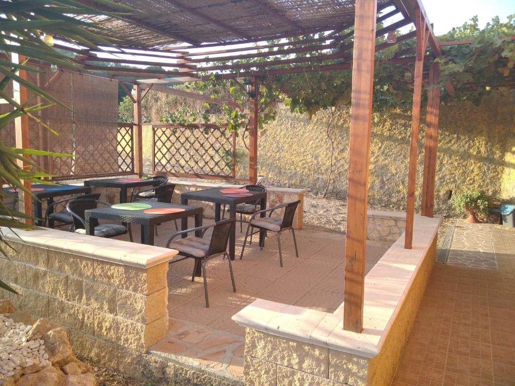 a patio with tables and chairs under a wooden pergola at Grotta Delle Fate in Ossi