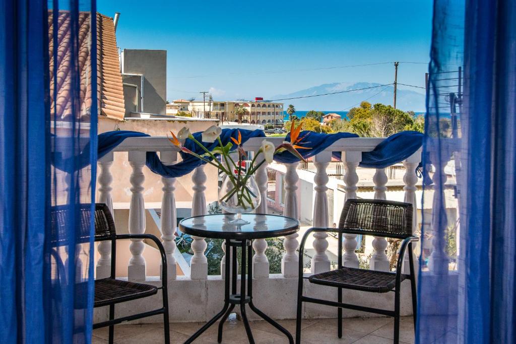 a table and chairs on a balcony with a vase of flowers at Anemomylos Studios Alykanas in Alikanas