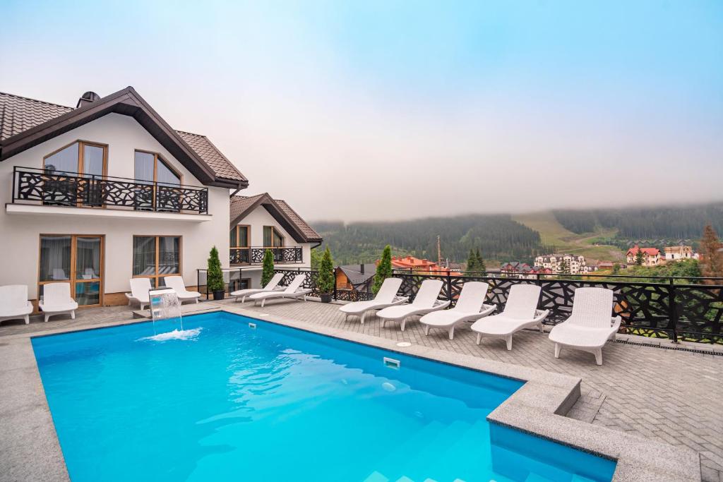 a swimming pool with chairs and a house at Chalet Fomich in Bukovel