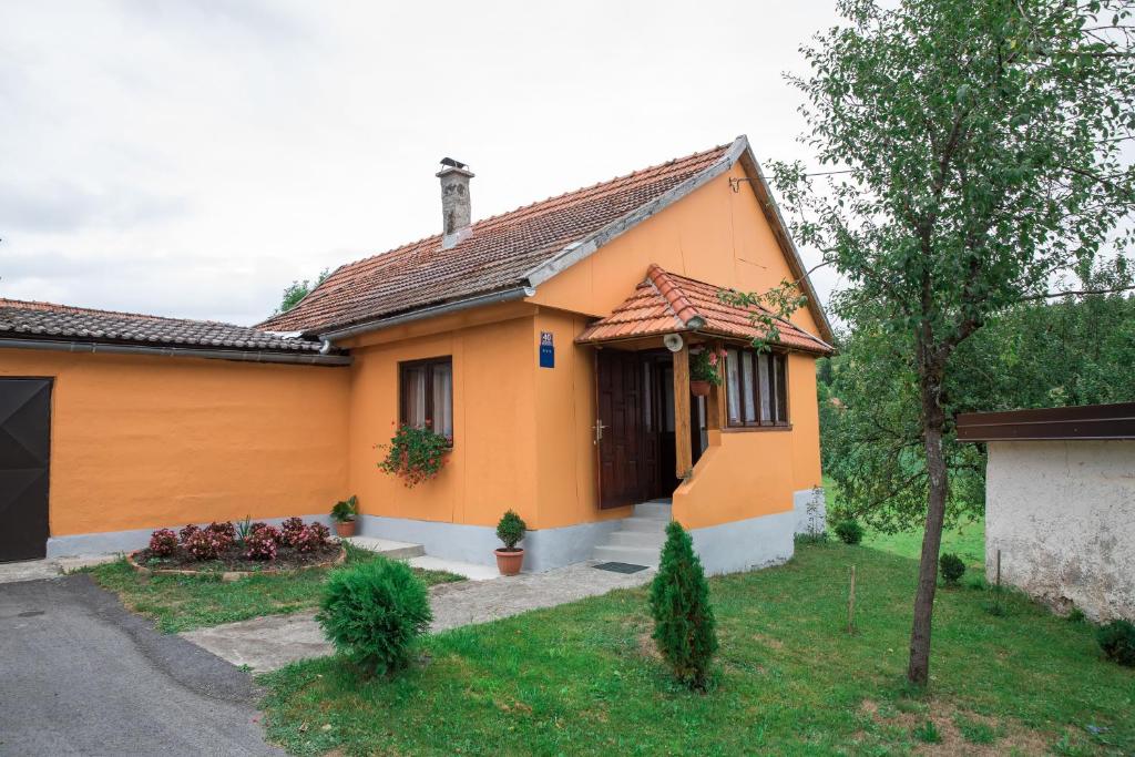 una pequeña casa amarilla con un árbol en el patio en Kuća za odmor Jagnjić, en Josipdol