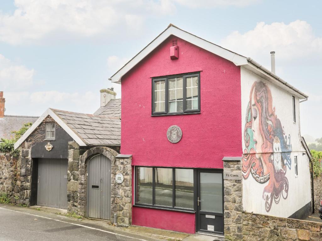 a red house with a painting on it at Ty Coets Coach House in Caernarfon