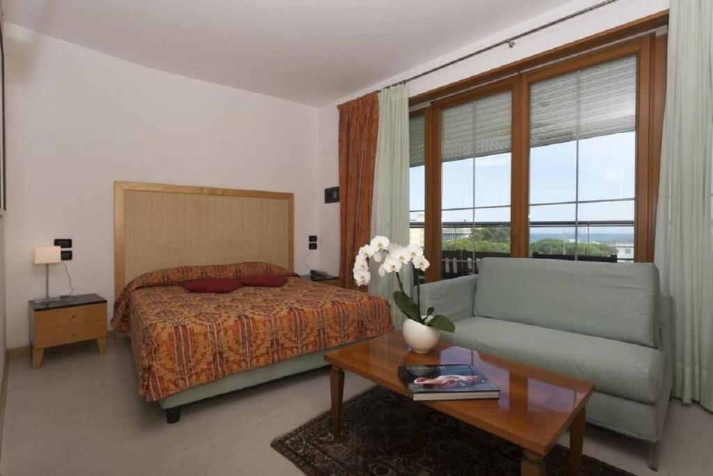 una camera da letto con un letto, un divano e un tavolo di Hotel Centrale a Lido di Jesolo